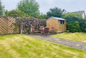 a backyard with a table and chairs and a wooden shed at Freeland Cottage in Dunoon