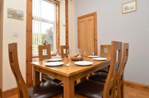 una mesa de comedor de madera con sillas y un bol de fruta en Freeland Cottage, en Dunoon