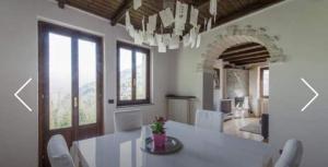 a dining room with a white table and white chairs at Villa Caterina in Perledo