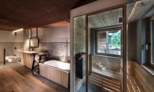 ein Bad mit einer Badewanne und einem Fenster in der Unterkunft Bad Ratzes in Seis am Schlern
