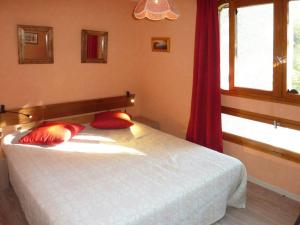 ein Schlafzimmer mit einem weißen Bett mit roten Kissen und einem Fenster in der Unterkunft Appartement Les Orres, 2 pièces, 6 personnes - FR-1-322-197 in Les Orres