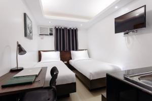 a hotel room with two beds and a desk at NEST NANO SUITES POBLACION-MAKATI in Manila