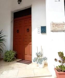 eine rote Tür eines Hauses mit Topfpflanzen in der Unterkunft Il rifugio dello scultore in Niscemi