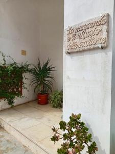 een bord aan de zijkant van een gebouw met planten bij La mansarda dello scultore in Niscemi