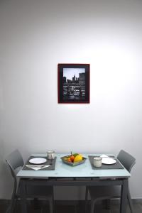 una mesa con un plato de fruta y una foto en la pared en LYDOY APARTMENT, en Reggio Calabria
