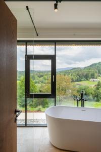 baño con bañera grande y ventana grande en steiRerBLiCke - Weingartenresidenz Guntschenberg 