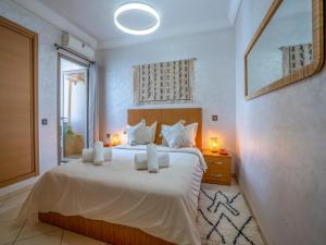 um quarto com uma cama grande com lençóis brancos e almofadas em ALIYA LUXURY APARTMENT El HOUDA-AGADIR em Agadir