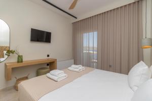 a white bedroom with a bed with towels on it at Artina in Marathopolis