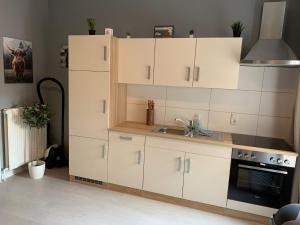 a kitchen with white cabinets and a sink and a stove at Stadtnah an der Förde 51 HH in Flensburg