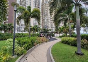 a walkway in a park with palm trees and a building at Fabulous View Circulo Verde, Manila QC in Manila