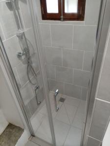 La salle de bains est pourvue d'une douche et d'une porte en verre. dans l'établissement Maison atypique corse, à Bastia
