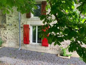 a red window on the side of a stone building at Le marronnier entre Les Buis in Bussière-Portevine