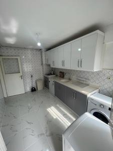 a kitchen with white cabinets and a white tile floor at Abbasi Apart in Bursa