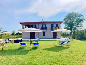 a group of lawn chairs and umbrellas in front of a house at Villa Dinesh in Sottomarina
