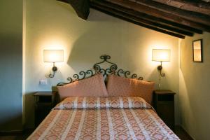 1 dormitorio con 1 cama con 2 lámparas en la pared en Locanda nel Cassero, en Civitella Marittima