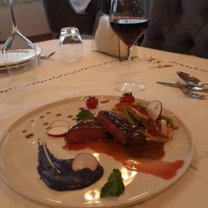 a plate of food on a table with a glass of wine at Hotel Mustang in Tirana