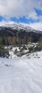 Una colina cubierta de nieve con una montaña al fondo en Cabaña Challhuaco, en San Carlos de Bariloche