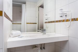 a white bathroom with a sink and a mirror at Hotel Dzingel in Tallinn