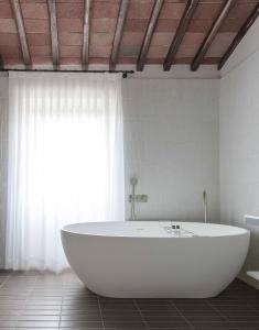 bañera blanca en una habitación con ventana en Pieve Aldina Relais & Châteaux en Radda in Chianti