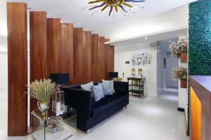 NEST NANO SUITES POBLACION-MAKATI في مانيلا: غرفة معيشة مع أريكة سوداء وجدار خشبي