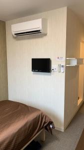 Habitación con cama y TV en la pared. en 阪南国际HOTEL en Hannan