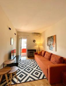 ein Wohnzimmer mit einem orangenen Sofa und einem Tisch in der Unterkunft Apartman Filip in Podgorica