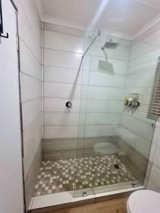 a shower with a glass door next to a toilet at 20 Brandersig in Jeffreys Bay +5 photos