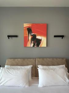 a bed with two pillows and a painting on the wall at The Victoria Lefkada in Lefkada Town