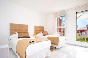 2 camas en una habitación blanca con ventana en Genteel Home Salvador Terrace, en Sevilla