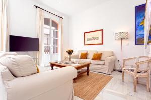sala de estar con muebles blancos y TV en Genteel Home Salvador Terrace, en Sevilla