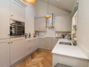 een keuken met witte kasten en een wit aanrecht bij Bluefin Cottage in Whitby