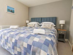 een slaapkamer met een blauw en wit bed met kussens bij Bluefin Cottage in Whitby
