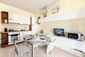 Il comprend une cuisine avec une table et des chaises ainsi qu'une télévision. dans l'établissement Anna Station Near Sea - Happy Rentals, à Sanremo