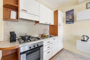 uma cozinha com armários brancos e um forno com placa de fogão em Anna Station Near Sea - Happy Rentals em Sanremo