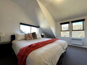 1 dormitorio con 1 cama grande y 2 ventanas en Cape Cod Chalet, alpine-getaways, en Dinner Plain