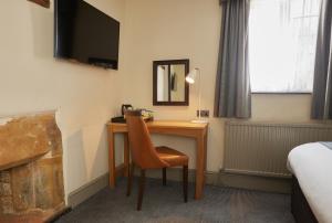 um quarto com uma secretária com uma cadeira e uma televisão em Red Lion Hotel by Greene King Inns em Banbury