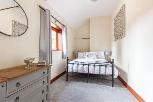 a bedroom with a bed with a mirror and a dresser at Woodrow End Cottage in Cawston