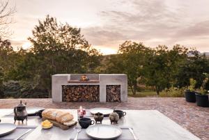 a table with plates of food and a fireplace at Avemore Vineyard View - wood fired hot tub and full power back up in Onder-Papegaaiberg