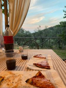 una mesa con dos rebanadas de pizza y una botella de vino en Torre medievale Balducci, en Vicopisano