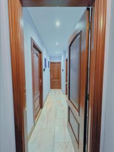um corredor com portas de madeira e piso em azulejo em Habitacion privado con baño privado en La Maresía em Cudillero