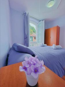 1 dormitorio con mesa y jarrón de flores púrpuras en Habitacion privado con baño privado en La Maresía, en Cudillero