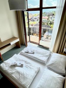a hotel room with two beds and a large window at Hotelový apartmán ALFRED C406 in Vysoke Tatry - Stary Smokovec