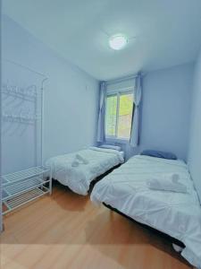 Duas camas num quarto com uma parede azul em Habitacion privado con baño privado en La Maresía em Cudillero