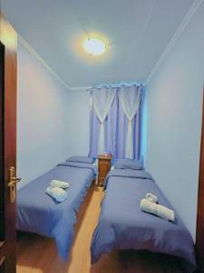 2 camas en una habitación con paredes azules en Habitacion privado con baño privado en La Maresía, en Cudillero