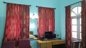 a room with two red curtains and a television at Mayem Lake View in Maem