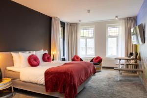 a hotel room with a large bed with red pillows at Dormio Wijnhotel Valkenburg in Valkenburg