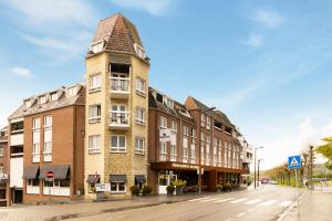 a tall brick building with a tower on a street at Dormio Wijnhotel Valkenburg in Valkenburg