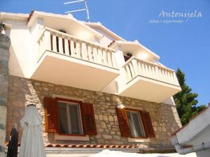 un gran edificio blanco con ventanas con persianas marrones en Apartment & Rooms Antonijela, en Bol