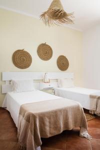 two beds in a white room with hats on the wall at Cerca Velha - Country House in Albufeira