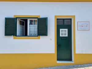 Casa da Avó Mirinha في Figueira e Barros: مبنى فيه باب أخضر ونافذة